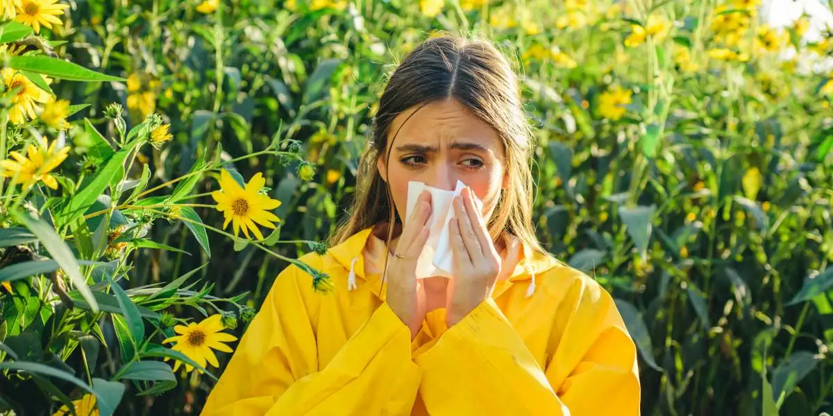 Woman sneezing from allergies next to flowers in Orlando, FL