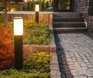 Two bollard lights next to a walkway at twilight. The Grasshoppers team can install lights like these and many other kinds as well.