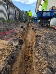 Grasshoppers technician with trench to be used for french drain in central florida property